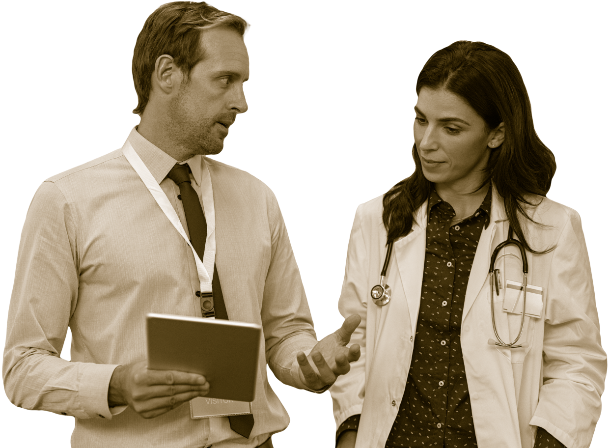 Man in button-up shirt and tie shows something on a clipboard or tablet to a woman doctor wearing a doctor coat and stethoscope
